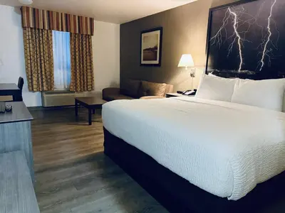 a hotel room with a large bed and a couch at Super 8 by Wyndham Dawson Creek in Dawson Creek