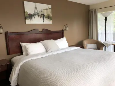 a bedroom with a large bed with white sheets at Piccadilly Motel in Radium Hot Springs