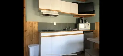 a kitchen with white cabinets and a sink and a microwave at Piccadilly Motel in Radium Hot Springs