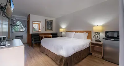 a hotel room with a large bed and a kitchen at Cedar Motel in Radium Hot Springs