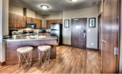 a kitchen with wooden floors and a counter with stools at Grand Inn & Residence- Grande Prairie in Grande Prairie