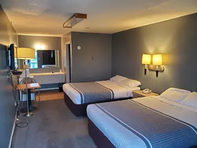 a hotel room with two beds and a television at Wild Rose Country Inn in Grande Prairie