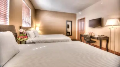 a hotel room with two beds and a desk at Podollan Inn & Spa - Grande Prairie in Grande Prairie