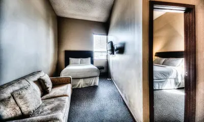 a room with two beds and a couch and a mirror at Podollan Inn & Spa - Grande Prairie in Grande Prairie