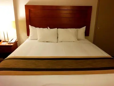 a bed with white sheets and pillows in a hotel room at St. Albert Inn & Suites in St. Albert