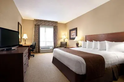 a hotel room with a bed and a flat screen tv at Days Inn & Suites by Wyndham Strathmore in Strathmore