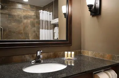 a bathroom with a sink and a mirror at Days Inn & Suites by Wyndham Strathmore in Strathmore