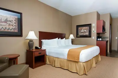 a hotel room with a large bed and a chair at Days Inn & Suites by Wyndham Strathmore in Strathmore