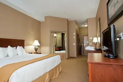 a hotel room with a bed and a flat screen tv at Days Inn & Suites by Wyndham Strathmore in Strathmore