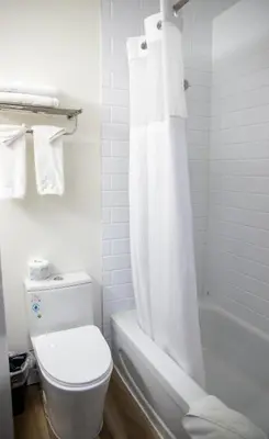 a white bathroom with a toilet and a shower curtain at Ramada by Wyndham Dawson Creek in Dawson Creek