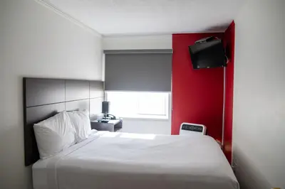 a bedroom with a white bed and a red wall at Ramada by Wyndham Dawson Creek in Dawson Creek