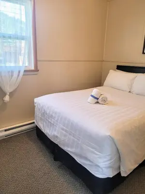a bedroom with a large white bed with a window at Lido Motel in Radium Hot Springs