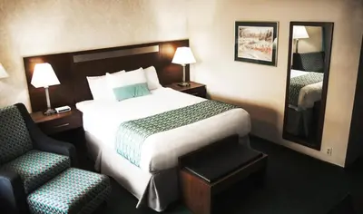 a hotel room with a bed and a chair at Ramada by Wyndham in Quesnel