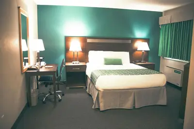 a hotel room with a large bed and a desk and a bed sidx sidx sidx at Ramada by Wyndham in Quesnel