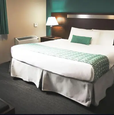 a large bed in a hotel room with a green pillow at Ramada by Wyndham in Quesnel