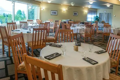a dining room filled with tables and chairs with tablesearcher at Hilltop Inn - Salmon Arm in Salmon Arm