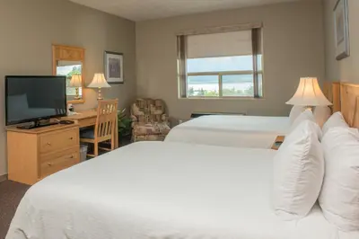 a hotel room with two beds and a flat screen tv at Hilltop Inn - Salmon Arm in Salmon Arm