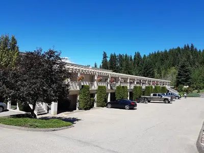 a building with cars parked in a parking lot at Hilltop Inn - Salmon Arm in Salmon Arm