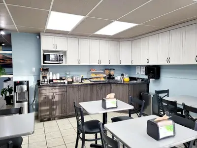 a kitchen with white tables and chairs and a counter at Canadian Motor Inn in Grande Prairie