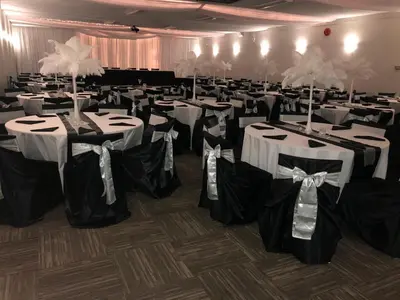 a banquet hall with white tables and black and white chairs at Northwood Plaza Hotel in Prince George