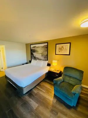a bedroom with a large bed and a chair at Super 8 by Wyndham 100 Mile House in One Hundred Mile House