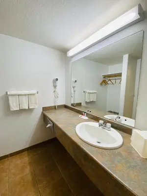 a bathroom with a sink and a large mirror at Super 8 by Wyndham 100 Mile House in One Hundred Mile House