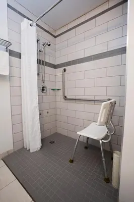 a shower with a white chair in a bathroom at Tower Inn & Suites in Quesnel