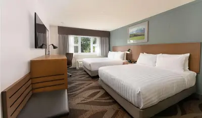 a hotel room with two beds and a television at Prestige Hudson Bay Lodge & Conference Centre, WorldHotels Crafted Collection in Smithers