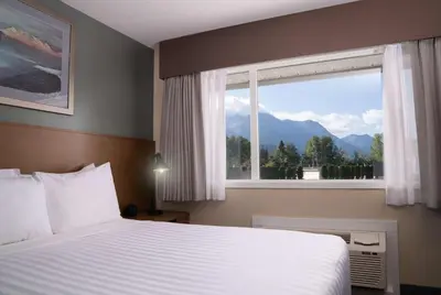 a bedroom with a bed and a window with a mountain view at Prestige Hudson Bay Lodge & Conference Centre, WorldHotels Crafted Collection in Smithers