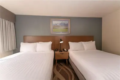 a hotel room with two beds and a night stand at Prestige Hudson Bay Lodge & Conference Centre, WorldHotels Crafted Collection in Smithers