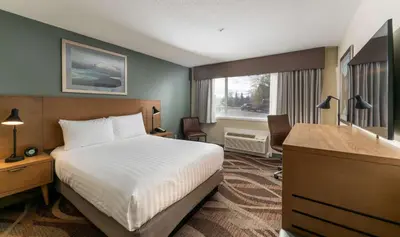 a hotel room with a bed and a desk and a window at Prestige Hudson Bay Lodge & Conference Centre, WorldHotels Crafted Collection in Smithers