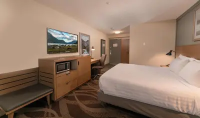 a hotel room with a bed and a desk and a tv at Prestige Hudson Bay Lodge & Conference Centre, WorldHotels Crafted Collection in Smithers