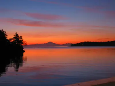 a sunset over a body of water at Sticks and Stones Cottage-Arbutus Grove in Galiano