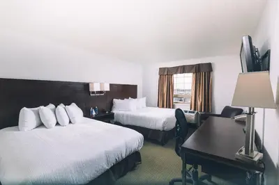 a hotel room with two beds and a desk at Service Plus Inns and Suites in Grande Prairie
