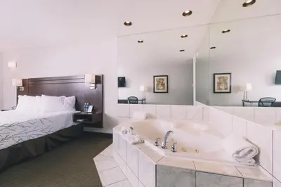a hotel room with a bath tub and a bed at Service Plus Inns and Suites in Grande Prairie