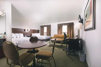 a hotel room with a bed and a table and chairs at Service Plus Inns and Suites in Grande Prairie