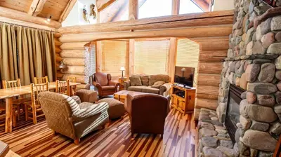 a living room with a stone fireplace in a log cabin at Snow Creek Cabins by Fernie Lodging Co in Fernie