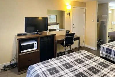 a hotel room with a desk with a tv and a bed at Rodeway Inn & Suites in Kamloops