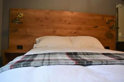 a bed with a wooden headboard and a blanket on it at Sasquatch Inn in Harrison Mills
