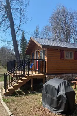 a small log cabin with a porch and a ramp at Rocky Mountain Cabins and Home in Golden