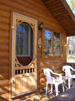 a log cabin with a door and chairs on the porch at Rocky Mountain Cabins and Home in Golden
