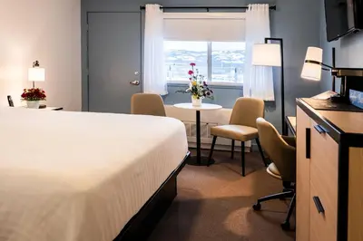 a hotel room with a bed and a table and chairs at SKKY Hotel in Whitehorse