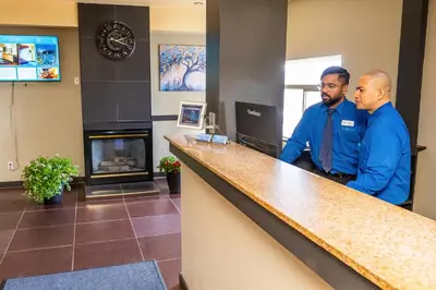 two men standing at a counter in a waiting room at SKKY Hotel in Whitehorse