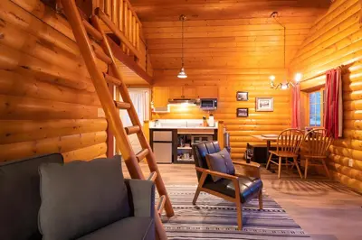 a living room with a staircase in a log cabin at Baker Creek By Basecamp in Lake Louise