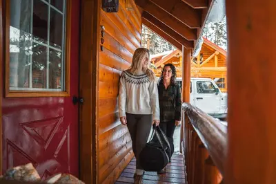 two women are standing on the porch of a cabin at Baker Creek By Basecamp in Lake Louise