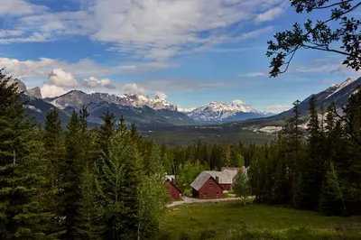 a house in a field with mountains in the background at Banff Gate Mountain Resort in Canmore