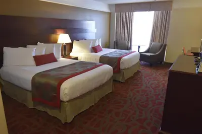 a hotel room with two beds and a chair at Tropical Inn - North Battleford in North Battleford