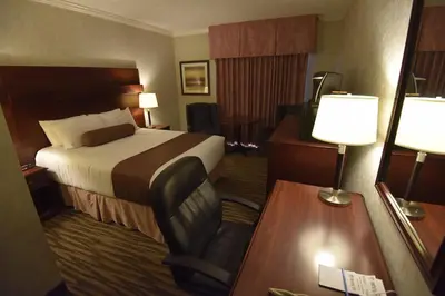 a hotel room with a bed and a chair at Tropical Inn - North Battleford in North Battleford