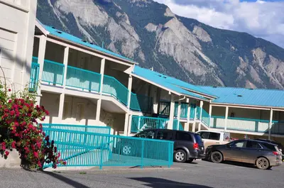 two cars parked in front of a building with a mountain at Canadas Best Value Inn Mile-0-Motel Lillooet in Lillooet