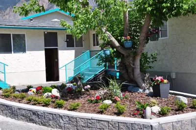 a garden in front of a house with a tree at Canadas Best Value Inn Mile-0-Motel Lillooet in Lillooet